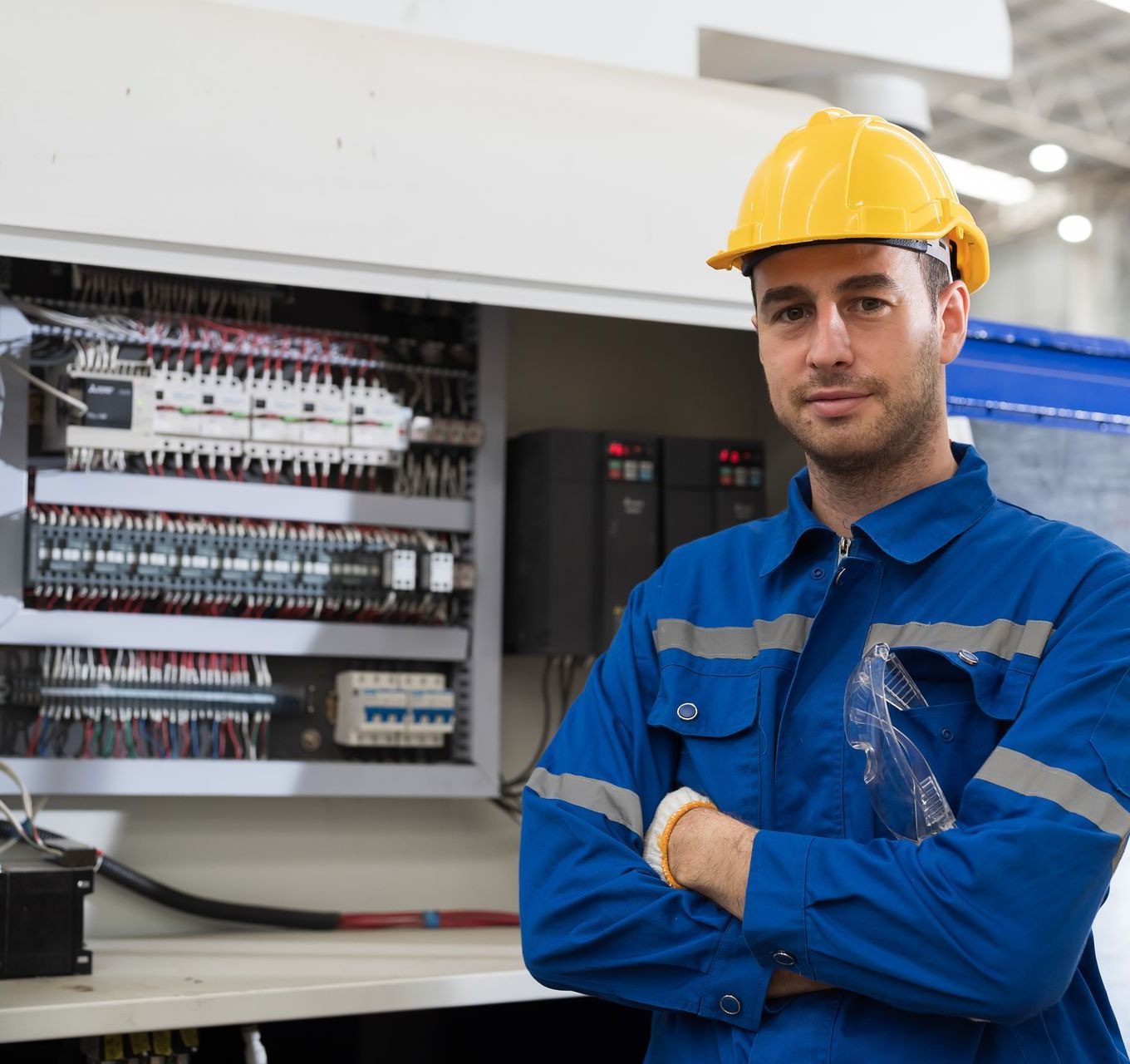A man wearing a hard hat is standing in front of a machine
