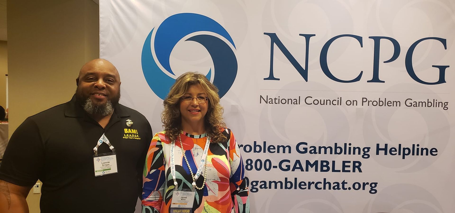 A man and a woman are posing for a picture in front of a sign that says ncpg.