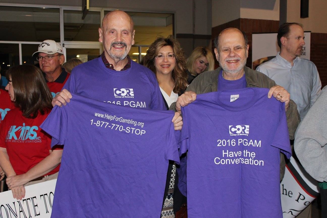 Two men are holding up purple shirts that say 2016 psam