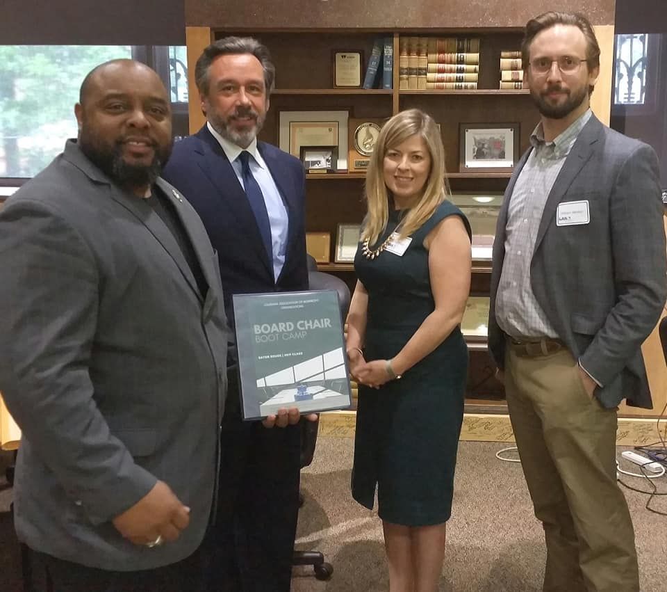 A group of people holding a book titled board chairs