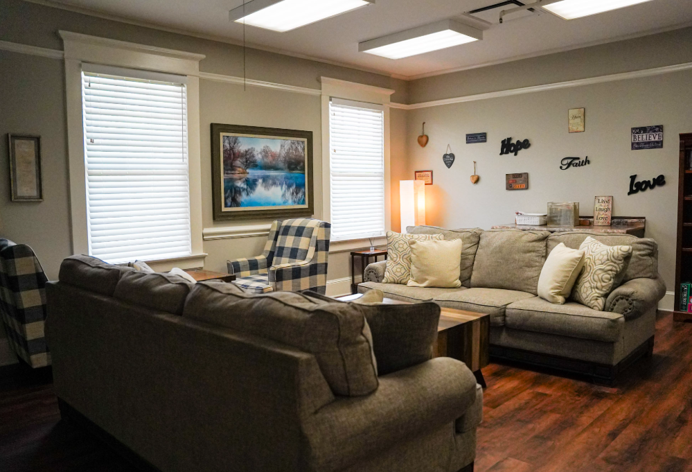 A living room with two couches , a chair , a table and a painting on the wall.