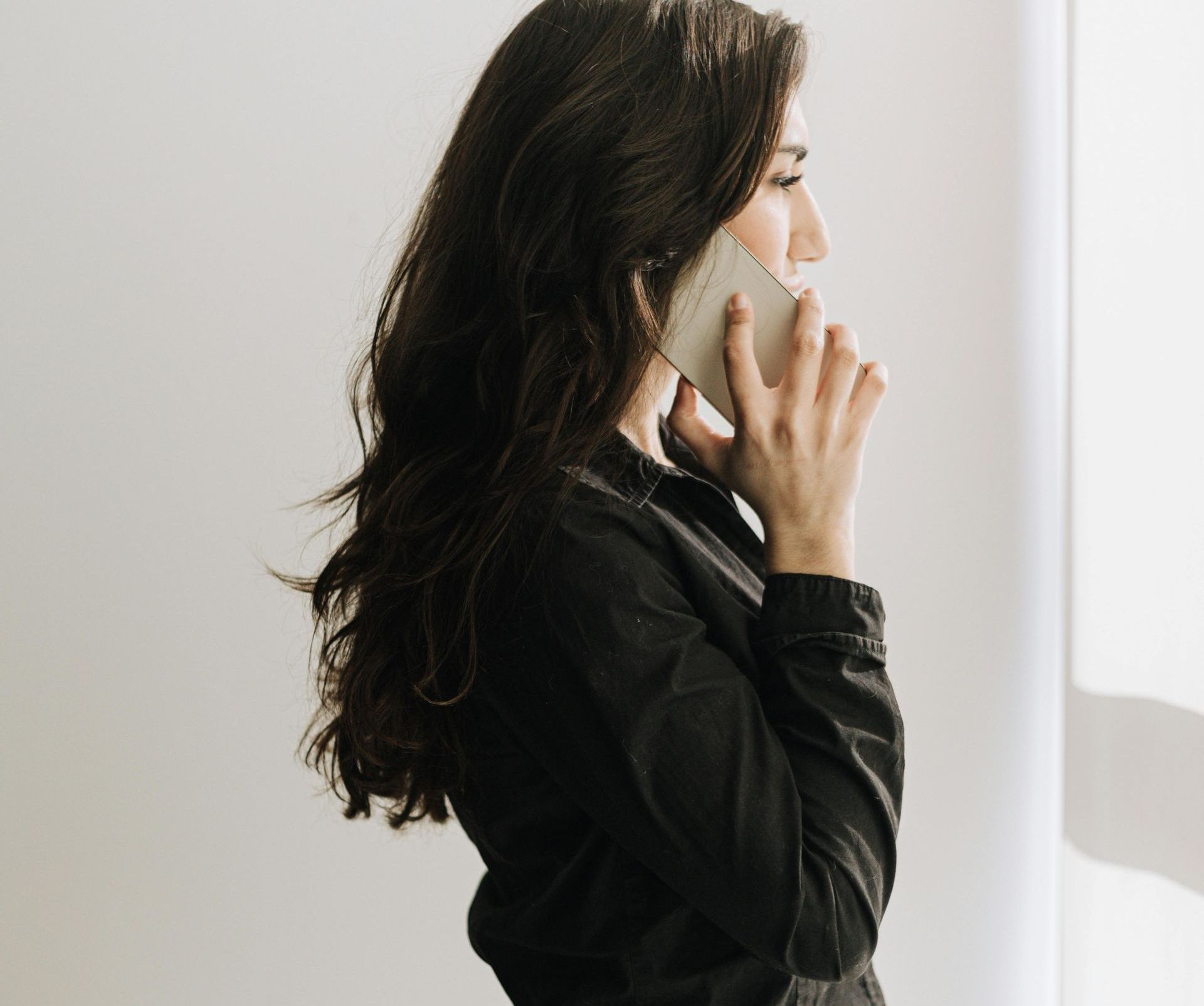 A woman in a black shirt is talking on a cell phone.