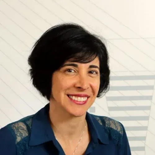 Uma mulher de camisa azul está sorrindo para a câmera.