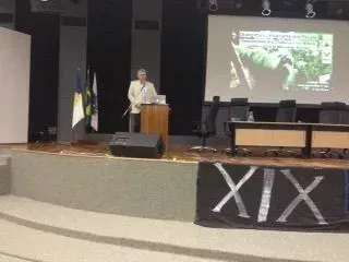Um homem está em um pódio em frente a uma tela que diz xix