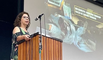 Uma mulher está em um pódio fazendo um discurso na frente de um microfone.