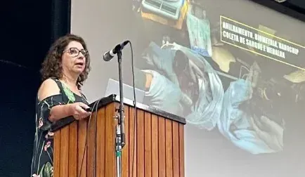 Uma mulher está em um pódio fazendo um discurso na frente de um microfone.