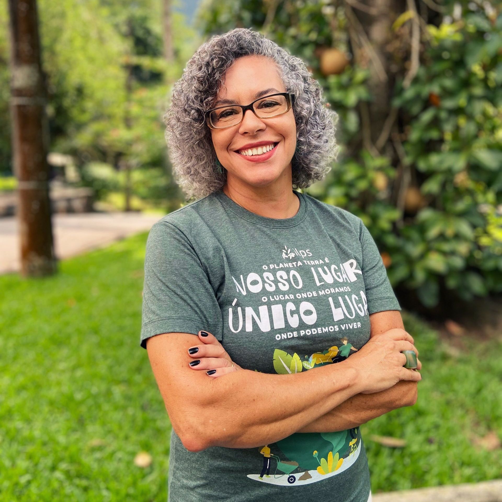 Uma mulher vestindo uma camiseta que diz seu lugar único lugar está sorrindo com os braços cruzados.