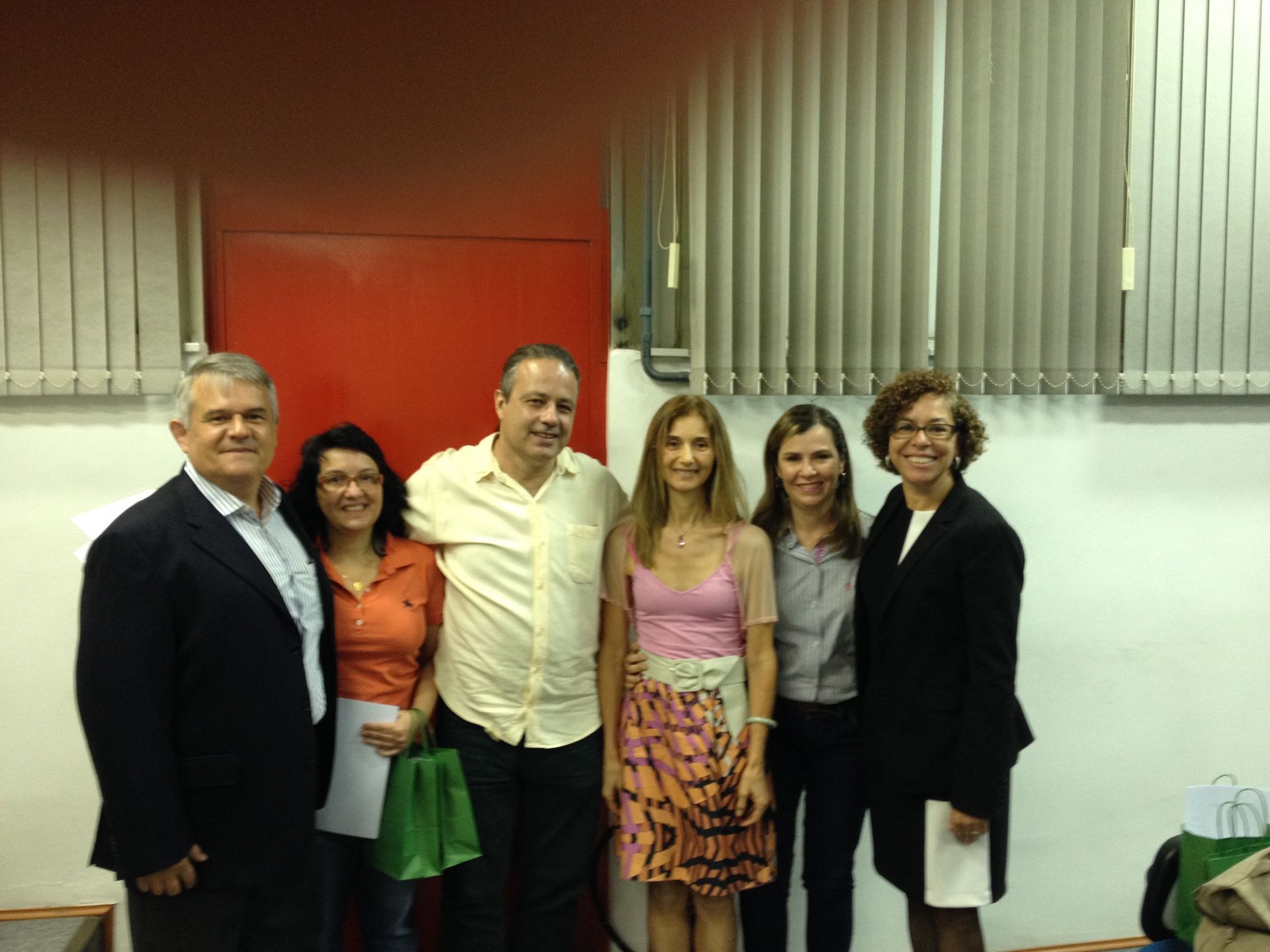 Um grupo de pessoas posando para uma foto em frente a uma porta vermelha