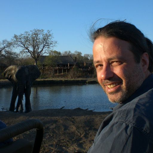 Um homem está sorrindo na frente de um elefante na água