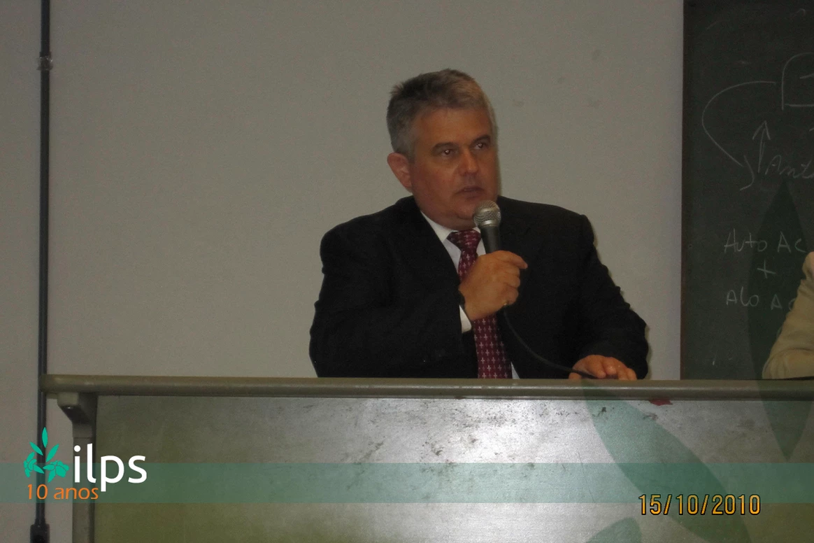 Um homem de terno e gravata está falando ao microfone
