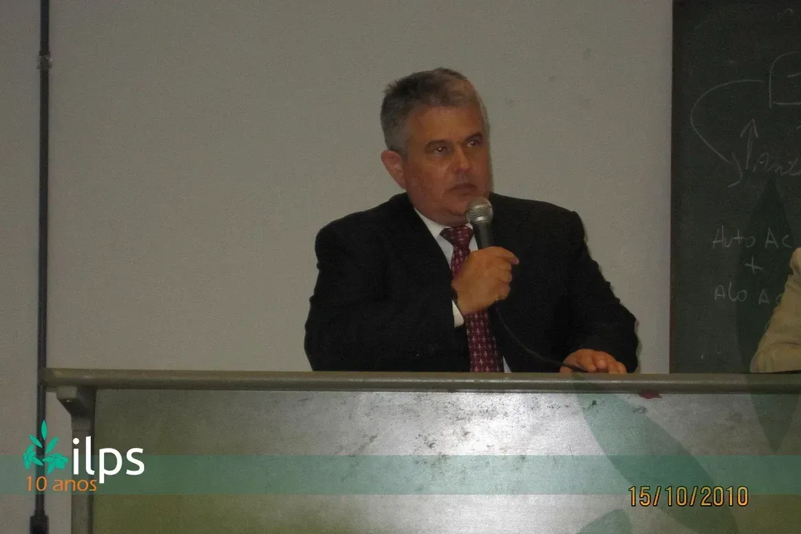 Um homem de terno e gravata está falando ao microfone