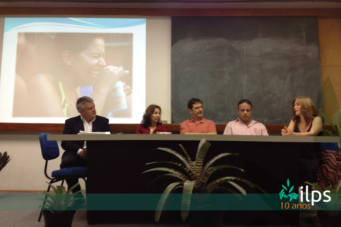 Um grupo de pessoas está sentado em uma mesa em frente a uma tela de projetor que diz itps