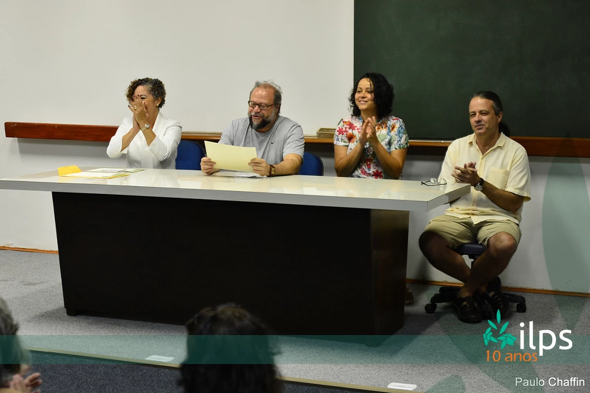 Um grupo de pessoas está sentado à mesa aplaudindo.