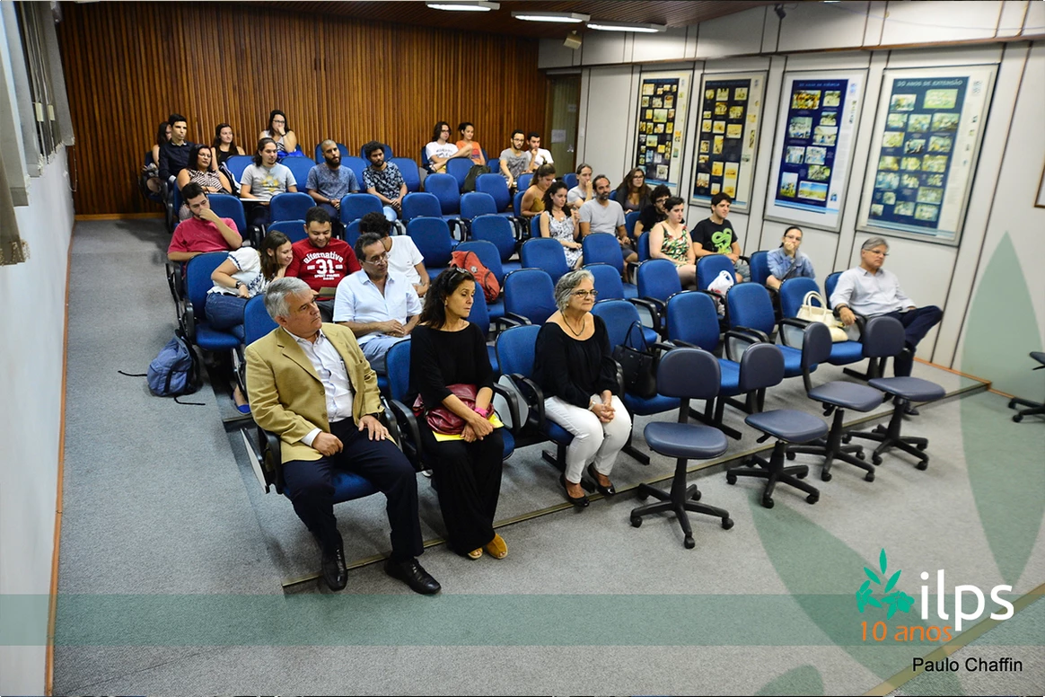Um grande grupo de pessoas está sentado em cadeiras em uma sala.