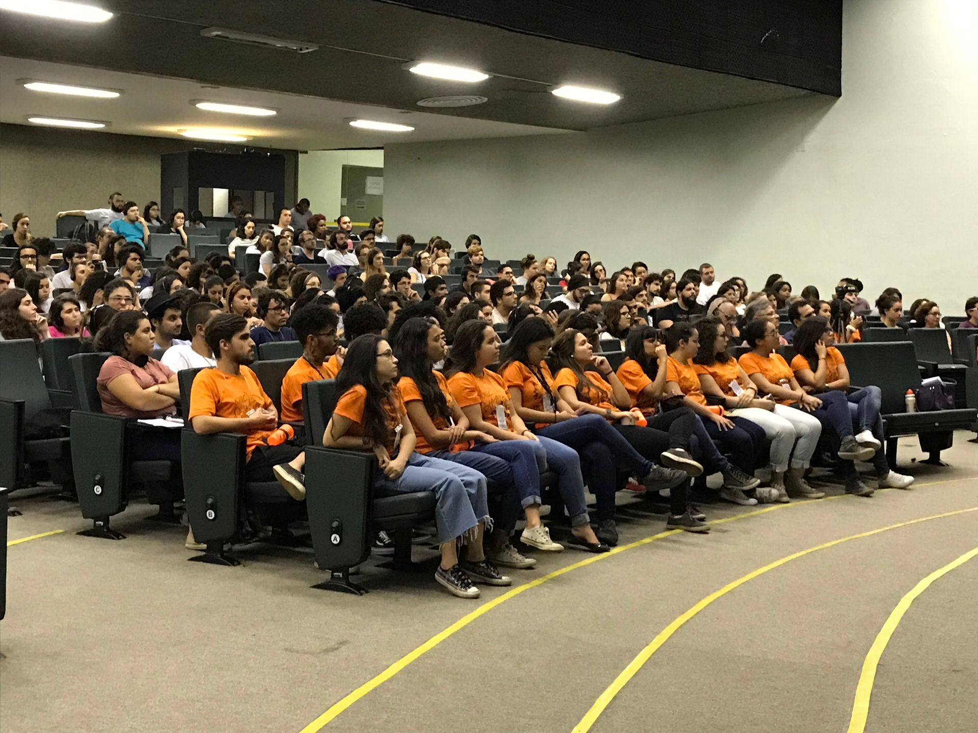 Um grande grupo de pessoas está sentado em uma sala de aula.