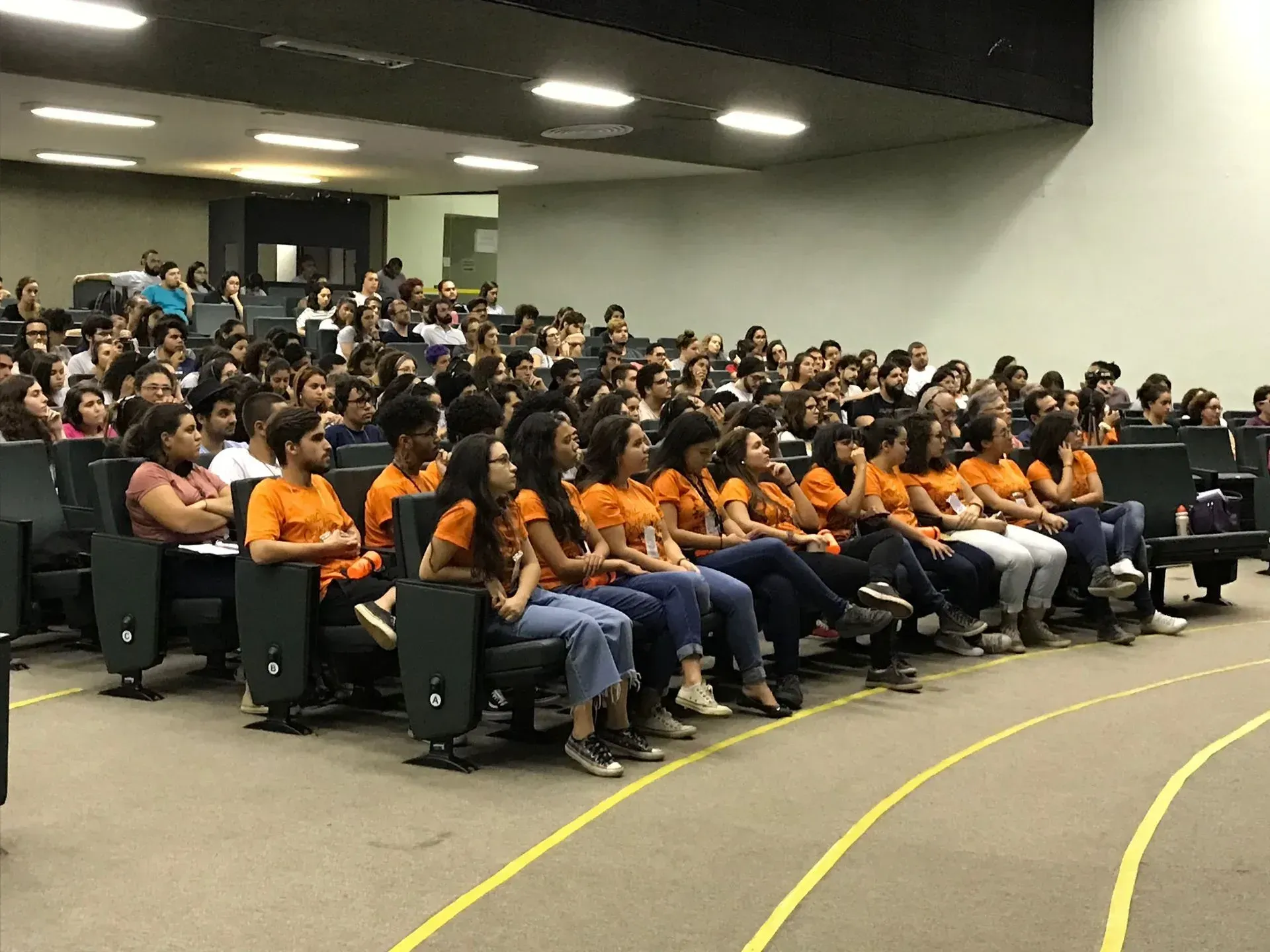 Um grande grupo de pessoas está sentado em uma sala de aula.