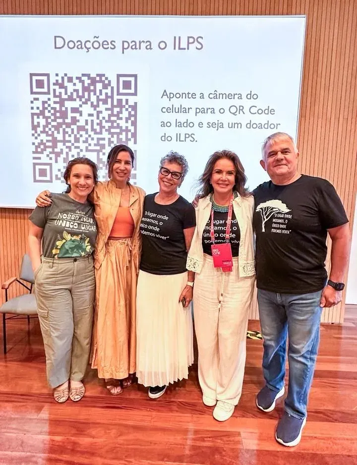Um grupo de pessoas posa para uma foto em frente a uma tela de projetor.