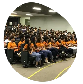 Um grande grupo de pessoas está sentado em uma sala de aula.
