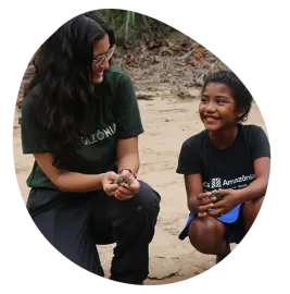 Mulher e menina segurando pequenas tartarugas na areia;