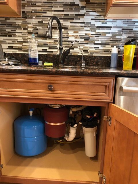 A kitchen sink with a blue tank underneath it.