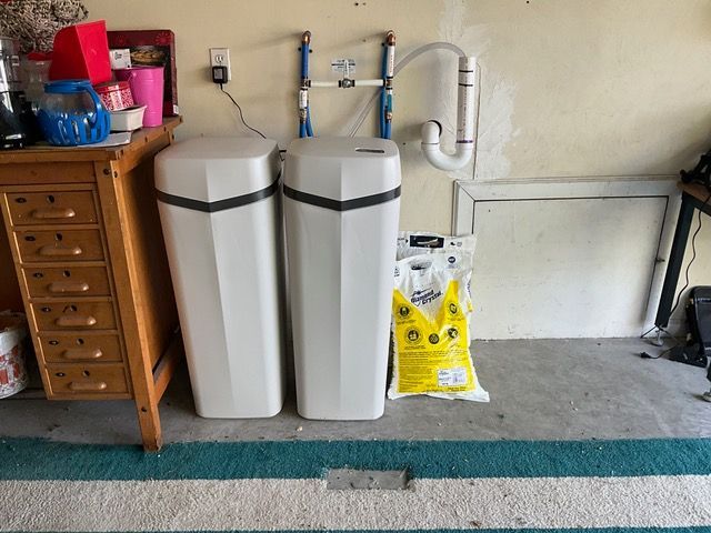 Two water filters are sitting next to each other in a garage.