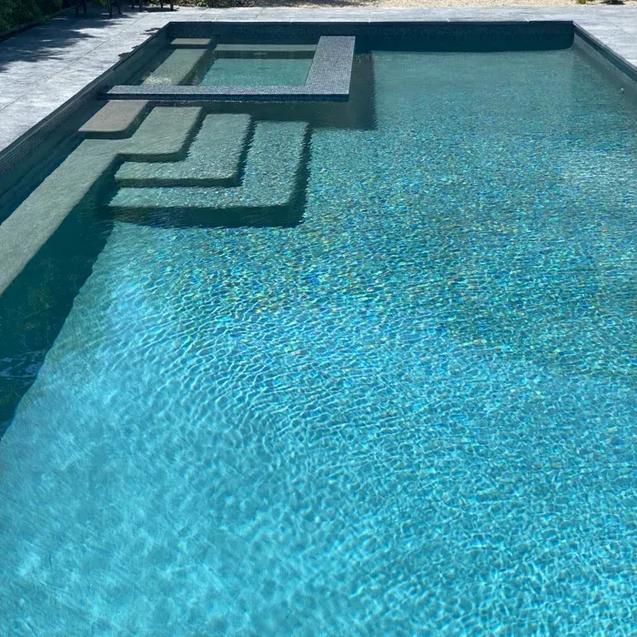 Blue swimming pool with shallow steps and a raised platform at one end