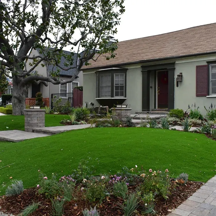Single-story suburban house with a manicured green lawn and landscaped front garden