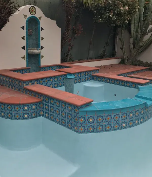 Terracotta-tiled pool with turquoise mosaic edging and a built-in fountain in a courtyard garden