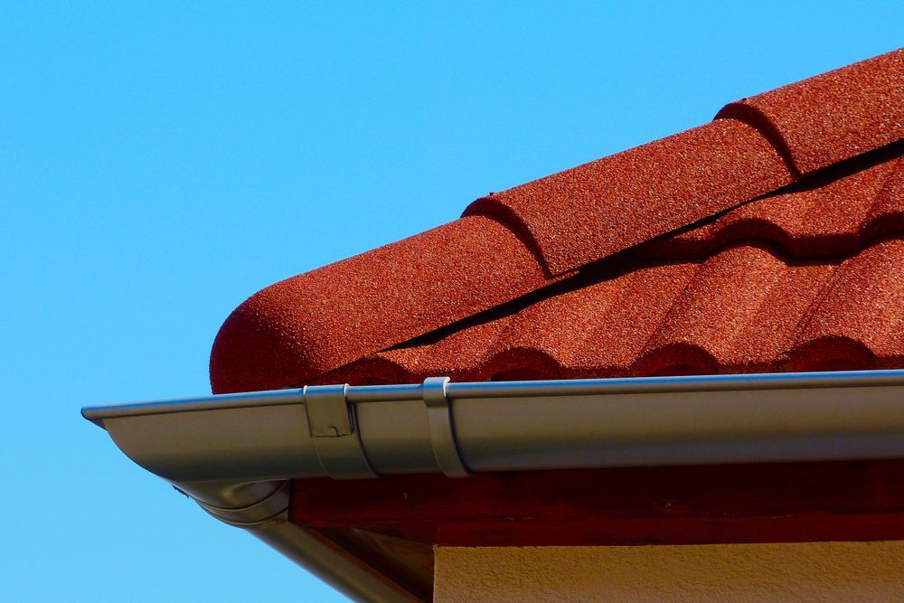A Close Up of a Red Tile Roof With a White Gutter — Wayne Treasure Roofing & Restoration In Forster, NSW