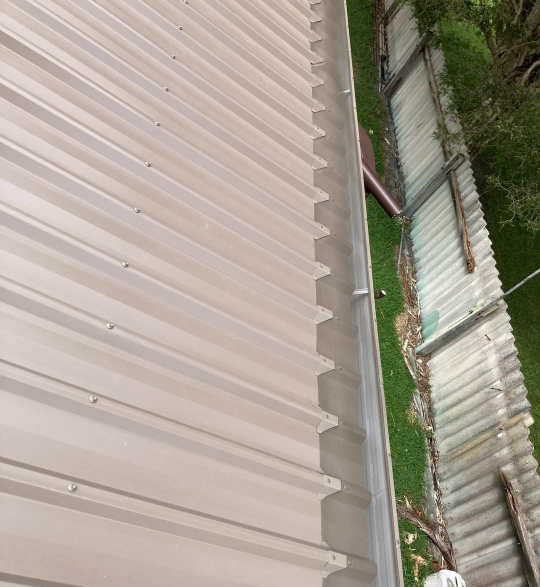 A gutter on the side of a building next to a fence. — Wayne Treasure Roofing & Restoration In Nabiac, NSW