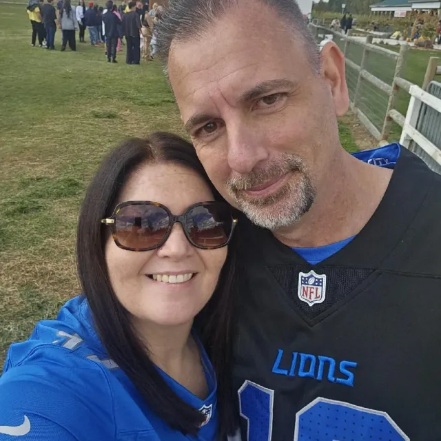 Selfie of two smiling fans in Lions gear at an outdoor field