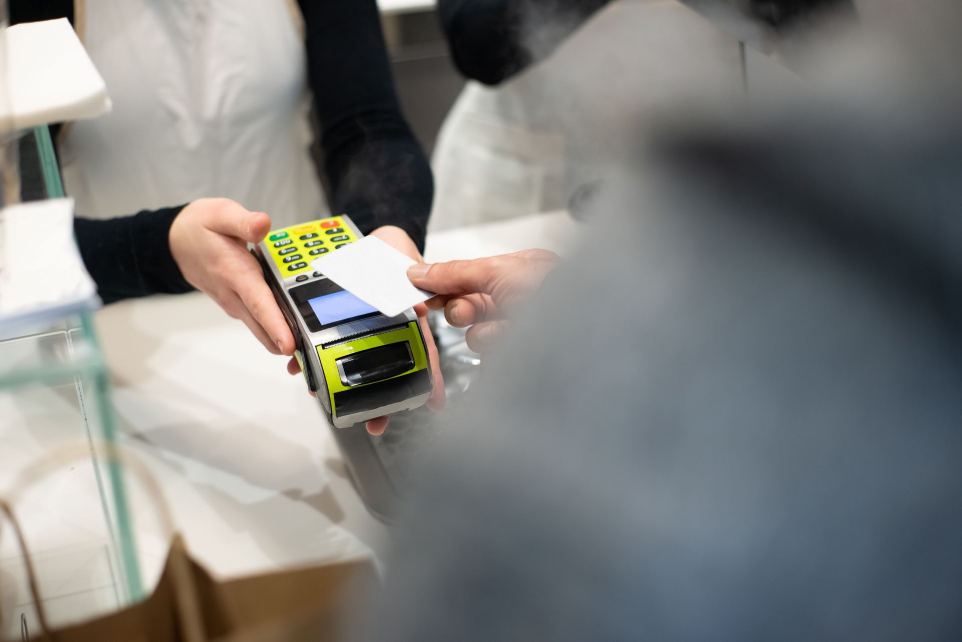 Hands holding a small boxed device in a store checkout area