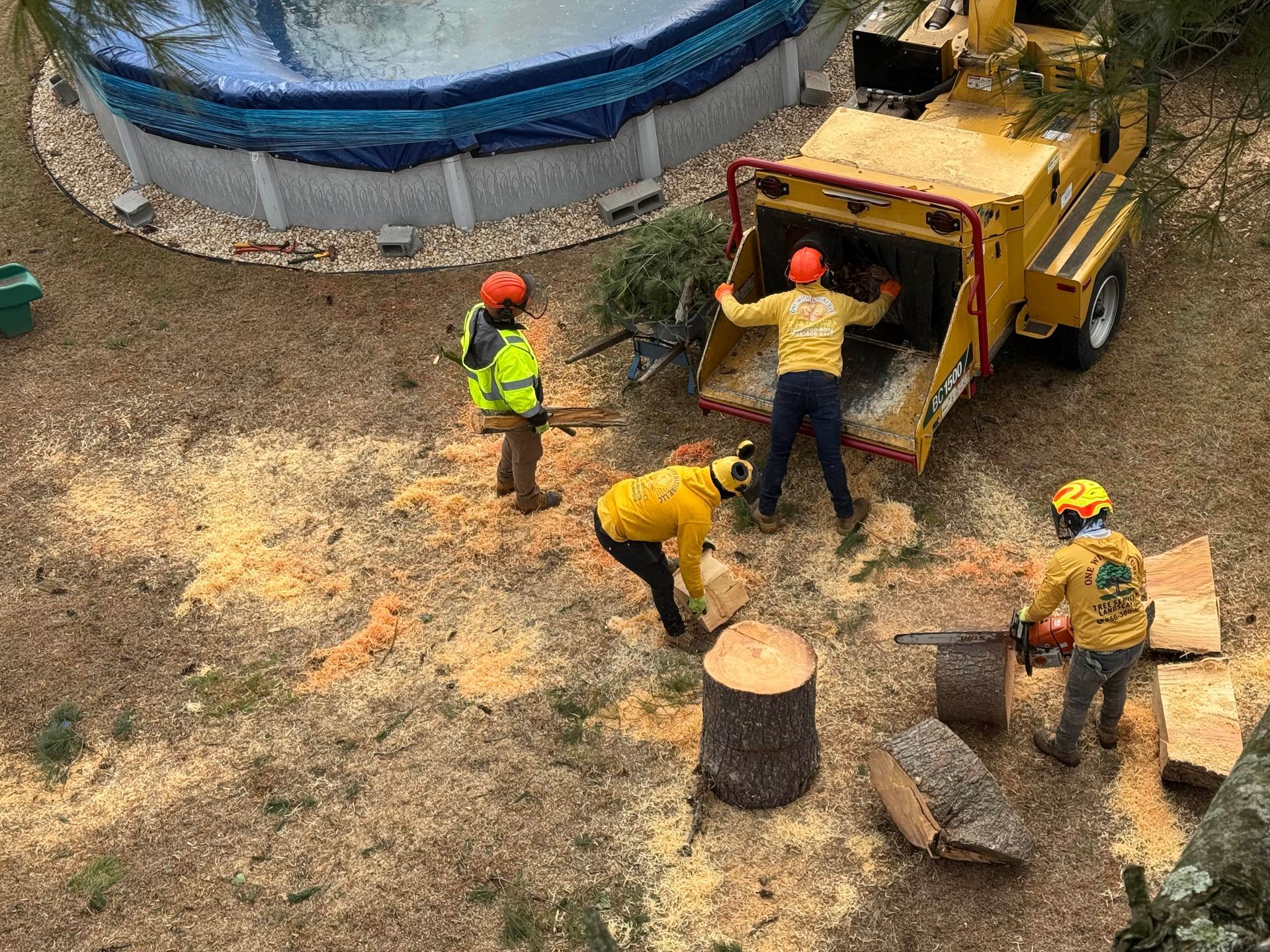 Workers in hard hats load debris into a truck at a construction site.