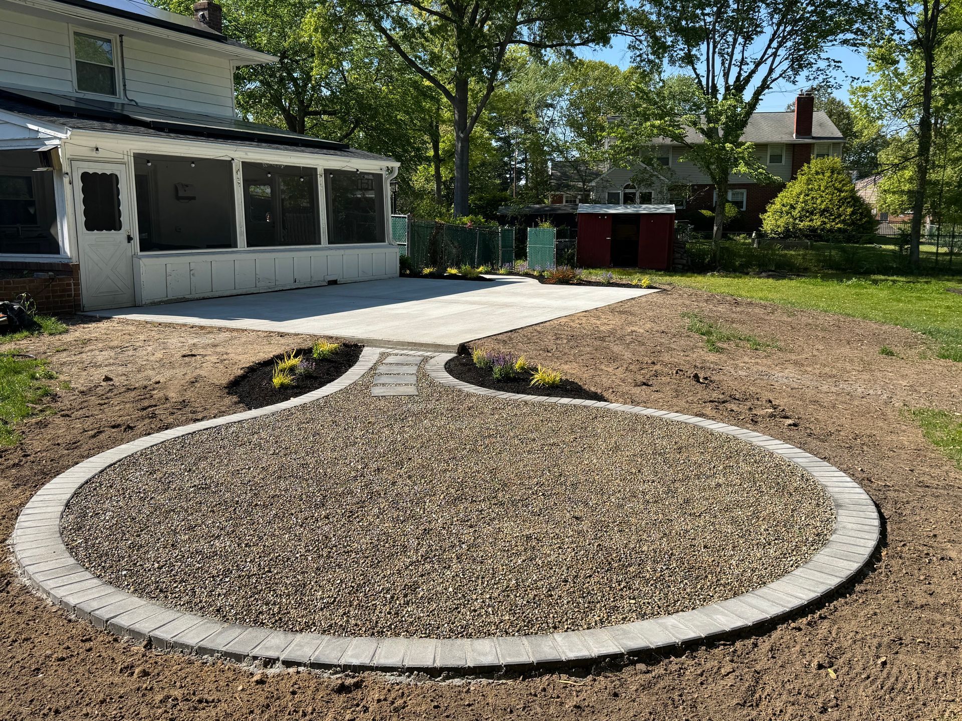 Backyard with a circular gravel bed, concrete border, and a house patio in the background