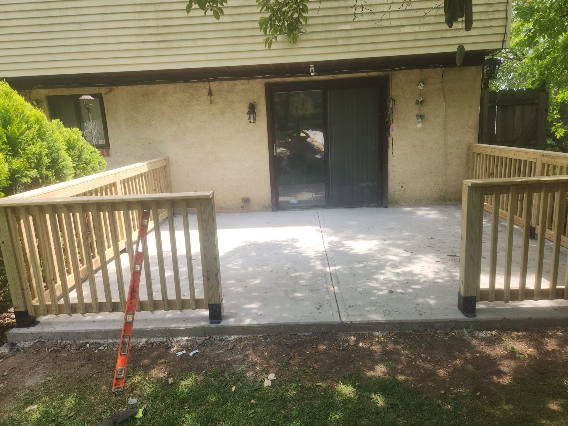 Front entrance with wooden accessibility ramp and railings leading to a dark double door.