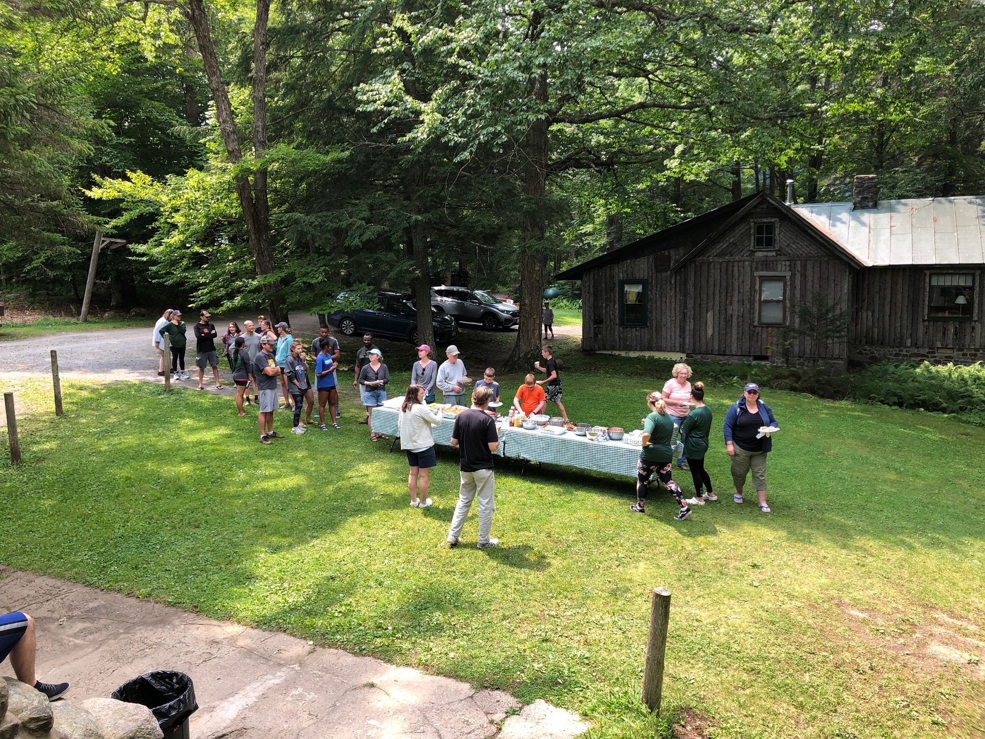 a group of people are standing around a table in a grassy field .
