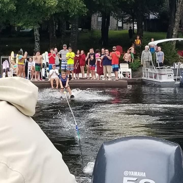 young child learning to waterski with people looking on
