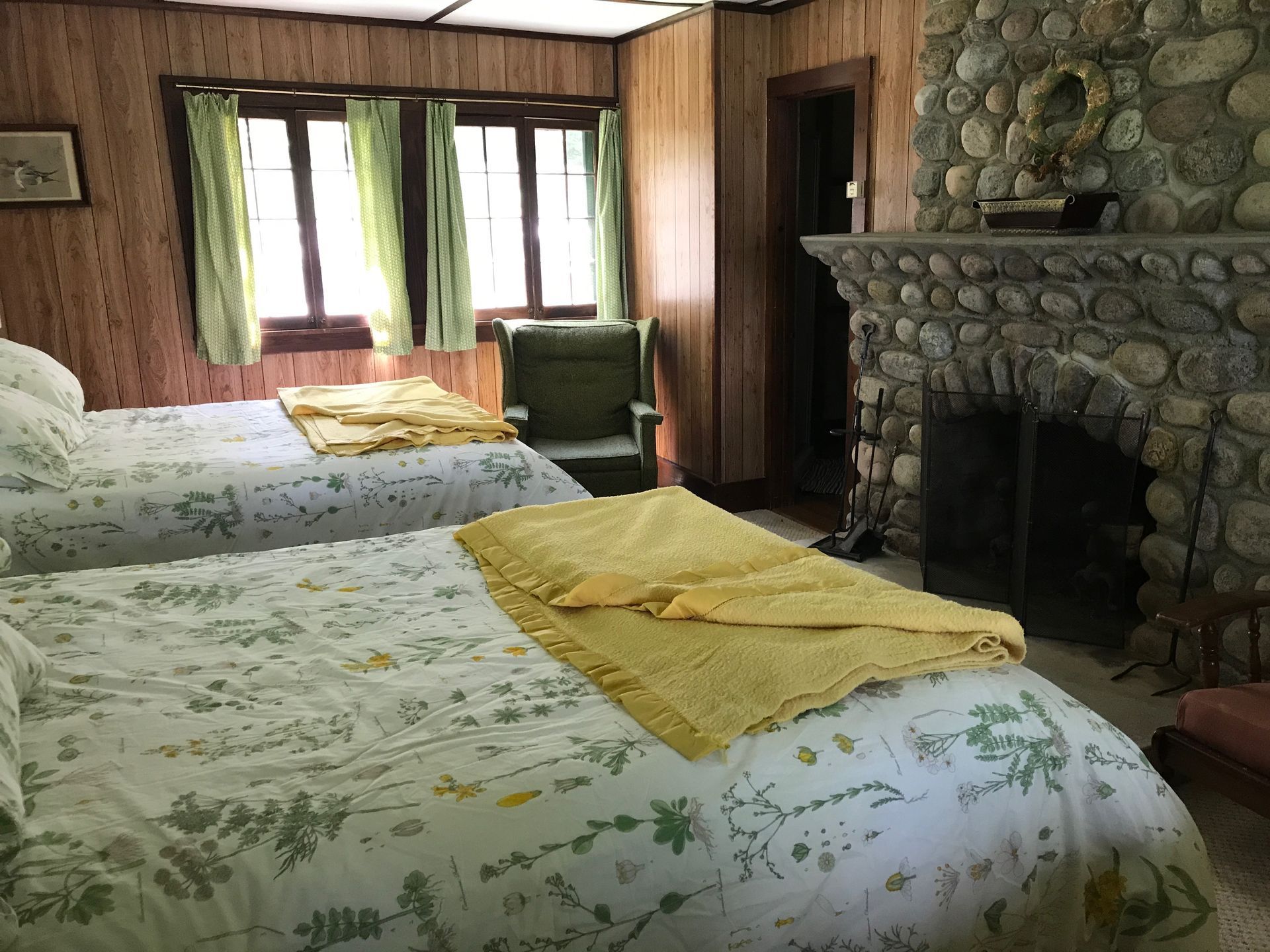 a bedroom with two beds , a chair and a fireplace .