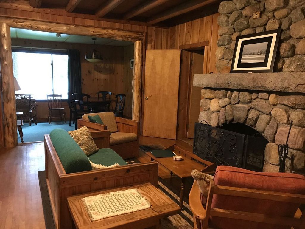 a living room with a stone fireplace and wooden furniture .