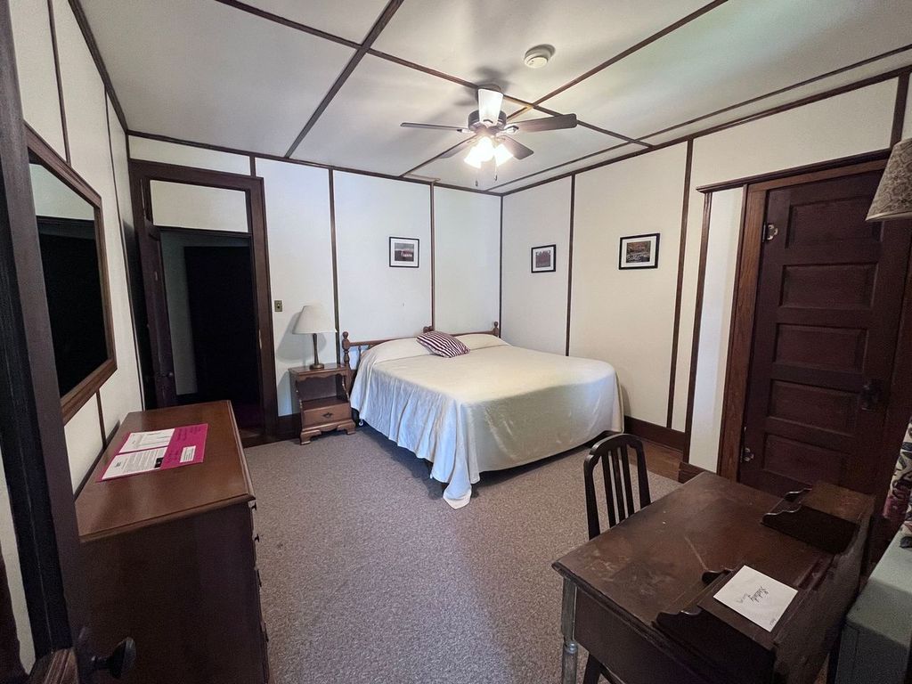 a bedroom with a bed , desk , mirror and ceiling fan .
