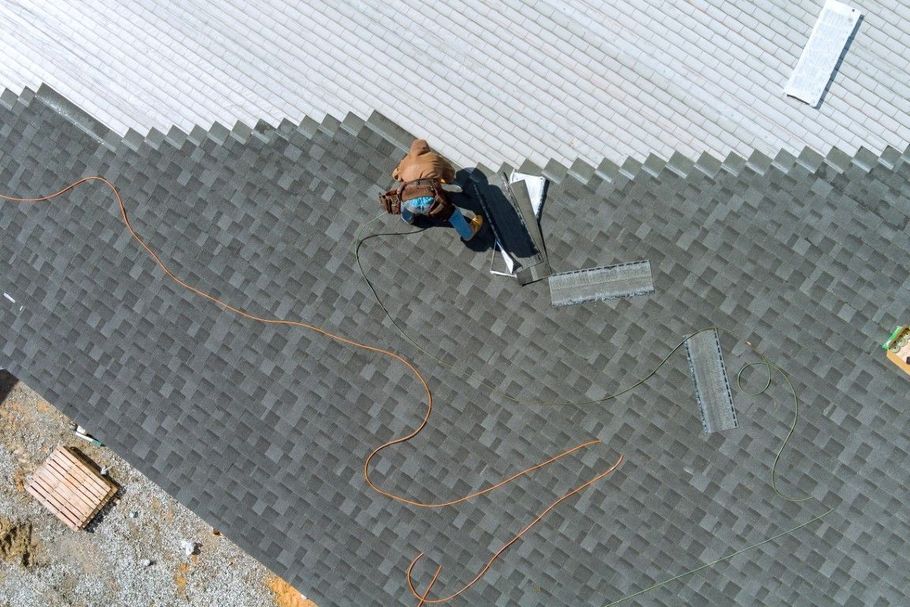Person in a blue jacket on a gray shingled roof beside orange chalk markings