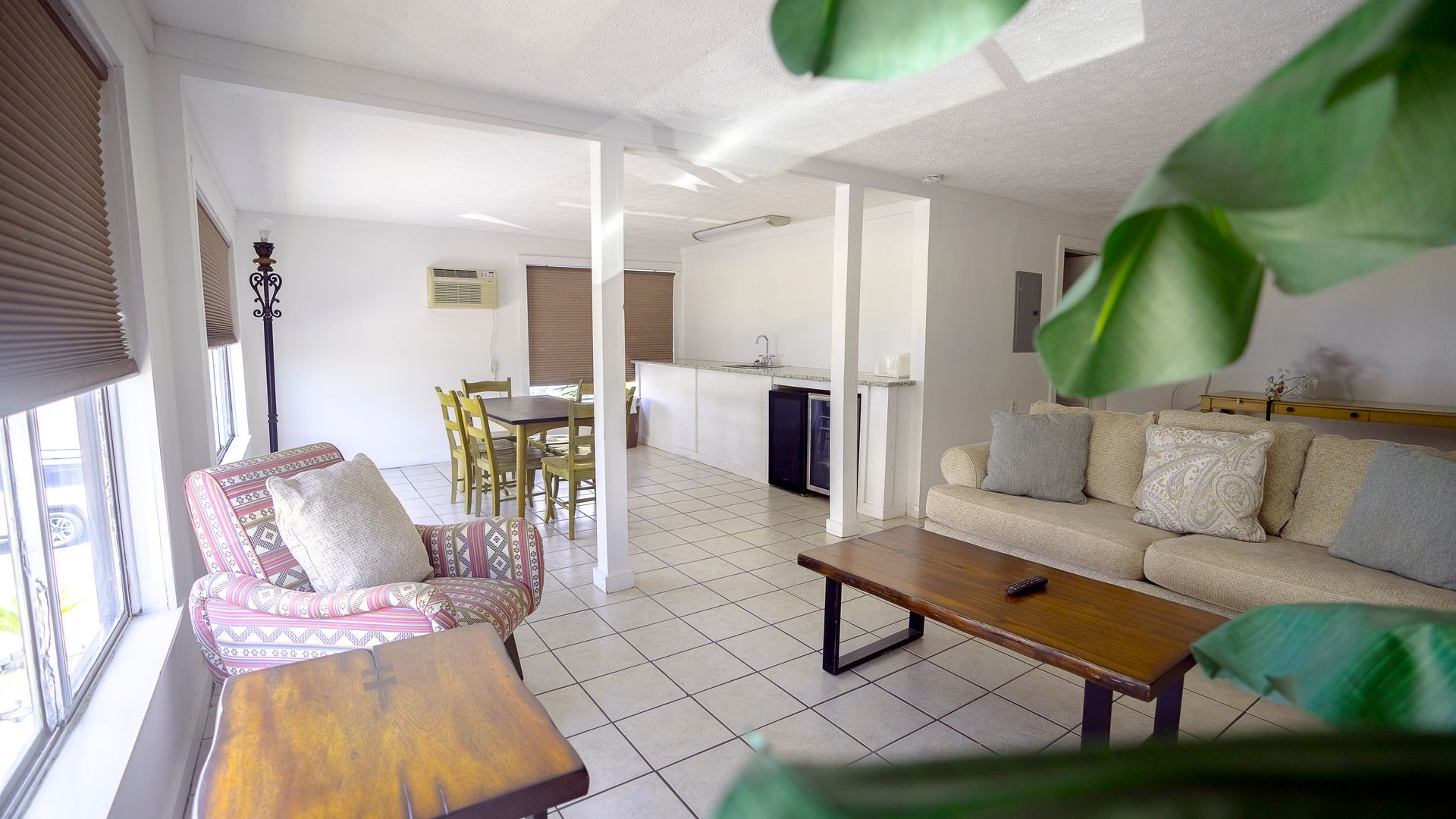 A living room with a couch , chair , coffee table and dining table.