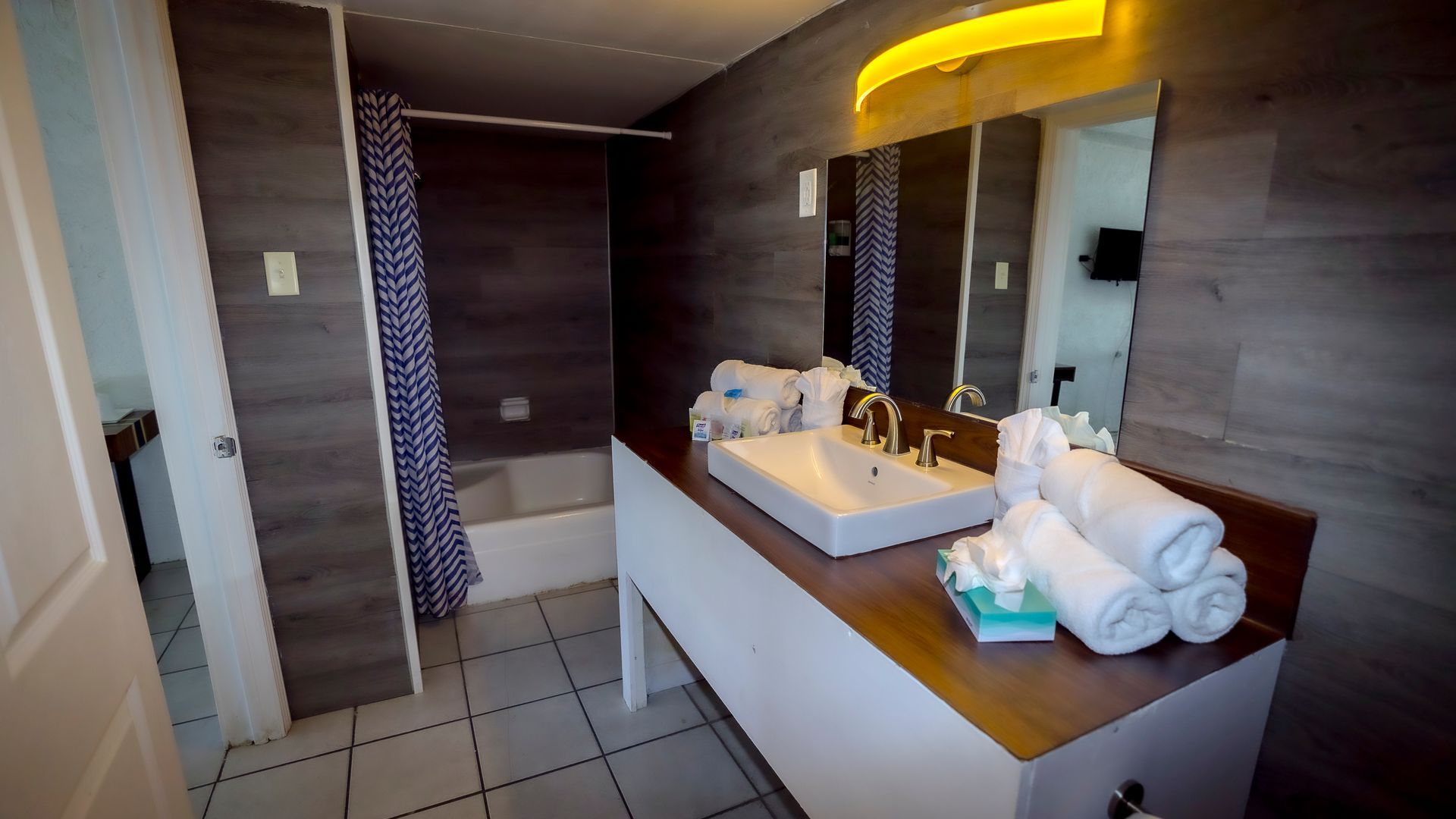 A bathroom with a sink , mirror and towels on the counter.