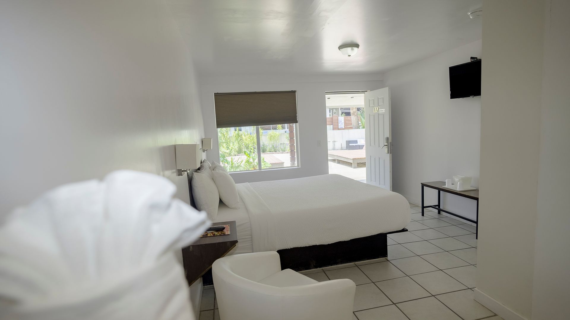 A hotel room with a bed , chair and television.