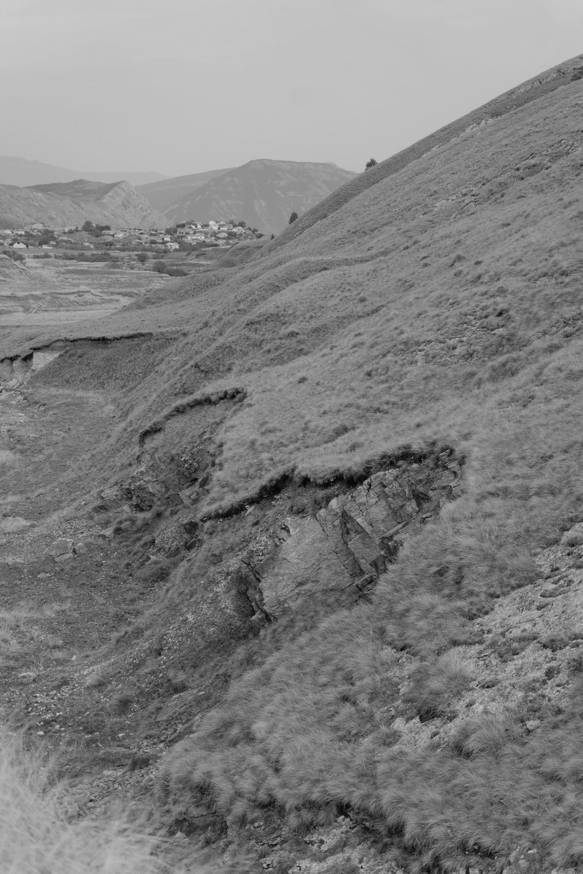 Black and white view of cascading water over a textured edge; frothy water in the background.