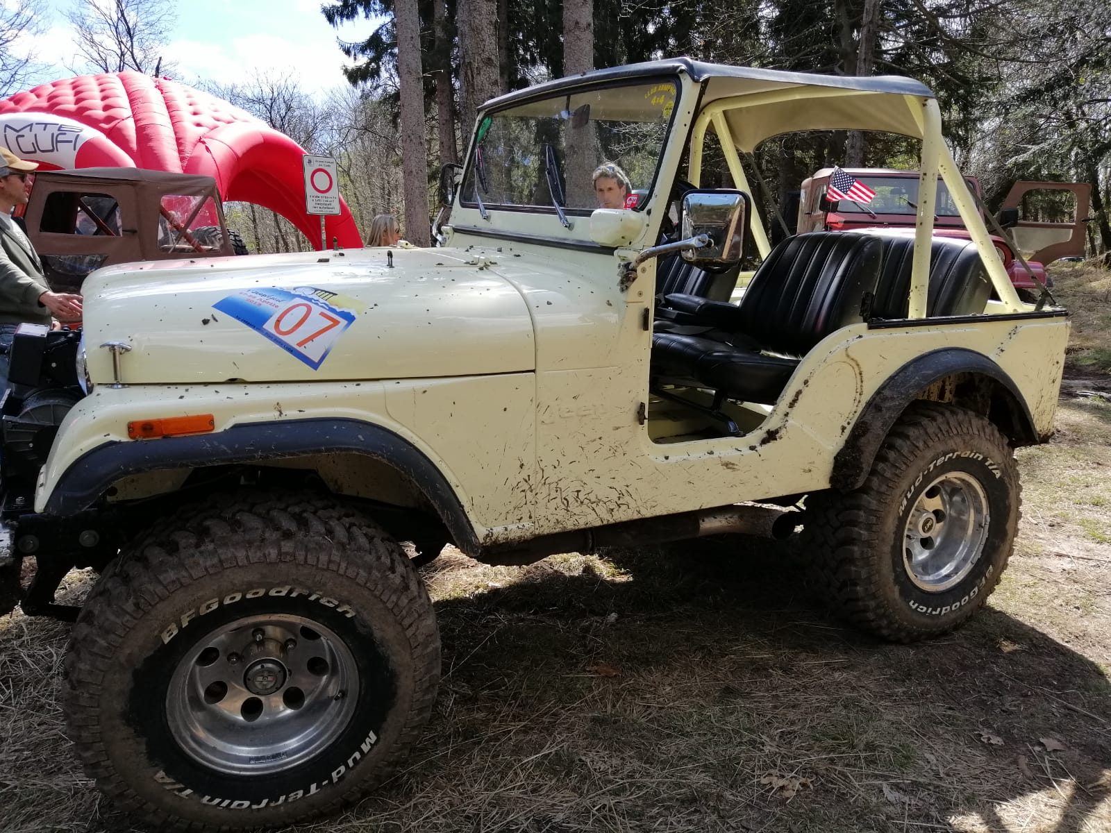 Jeep gialla con roll-bar, pneumatici fangosi e numero 07 sul cofano, parcheggiata all'aperto sull'erba.