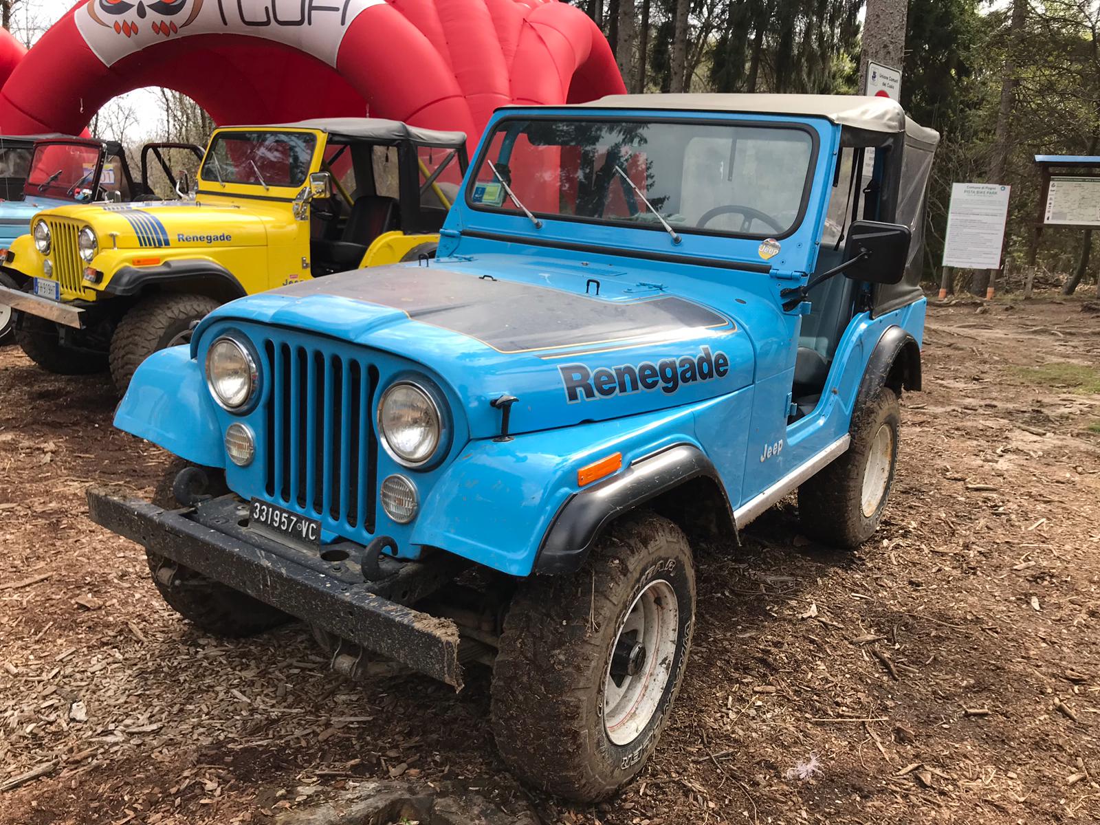 Una Jeep Renegade blu con il cofano nero, parcheggiata all'aperto vicino ad altre Jeep.