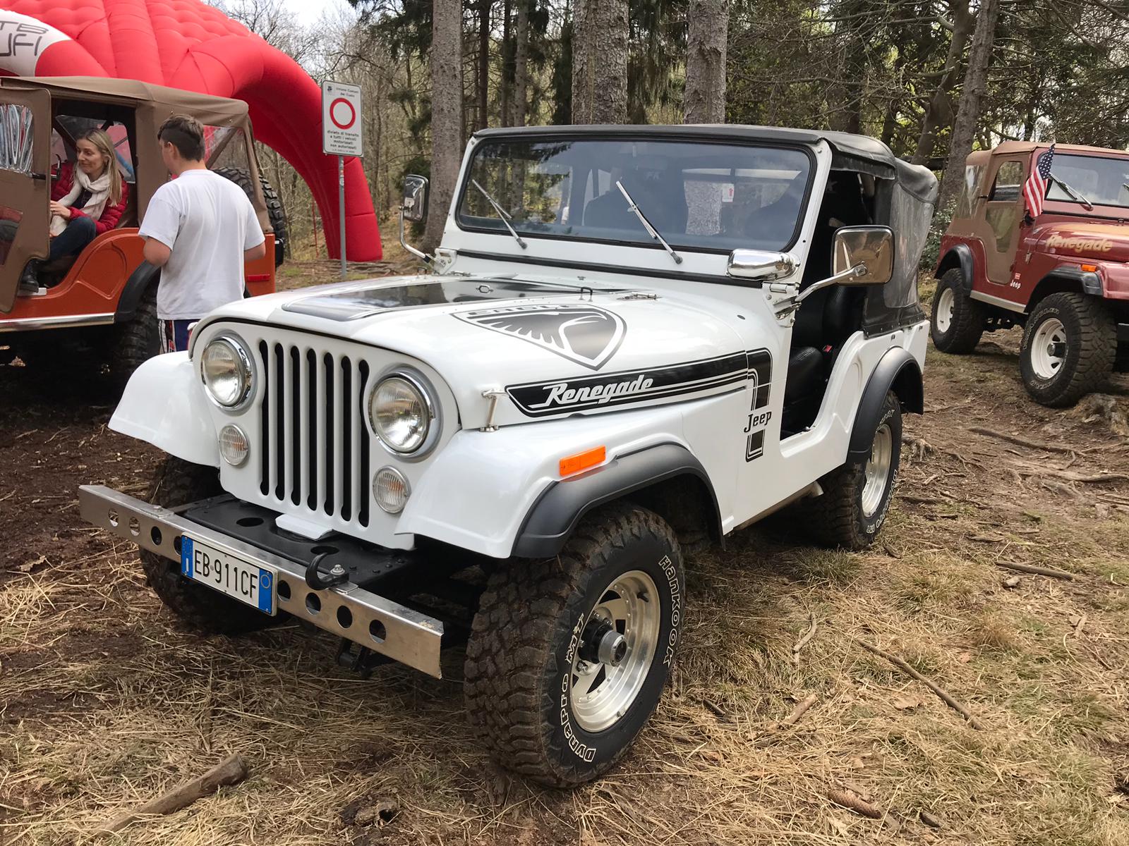 Una Jeep Renegade bianca parcheggiata all'aperto con altre due Jeep nelle vicinanze.