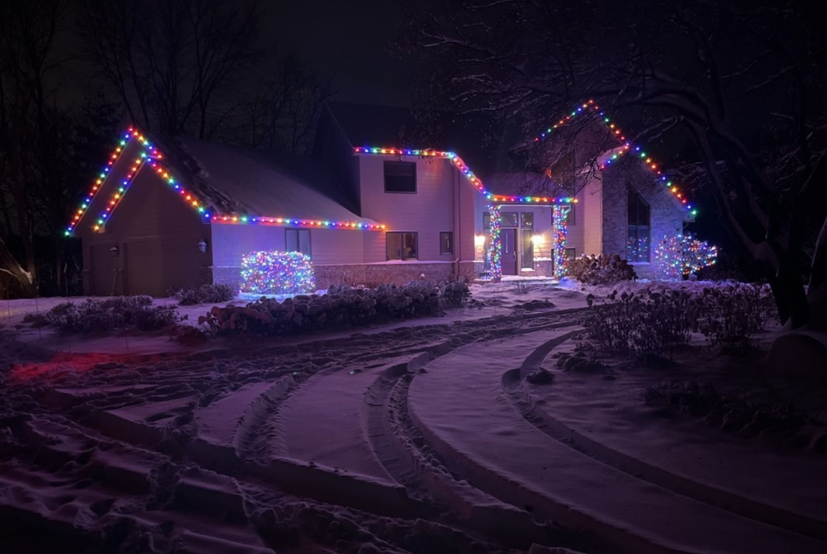 Holiday lights glowing through trees and rooftops in Victoria, MN&rsquo;s Laketown neighborhood