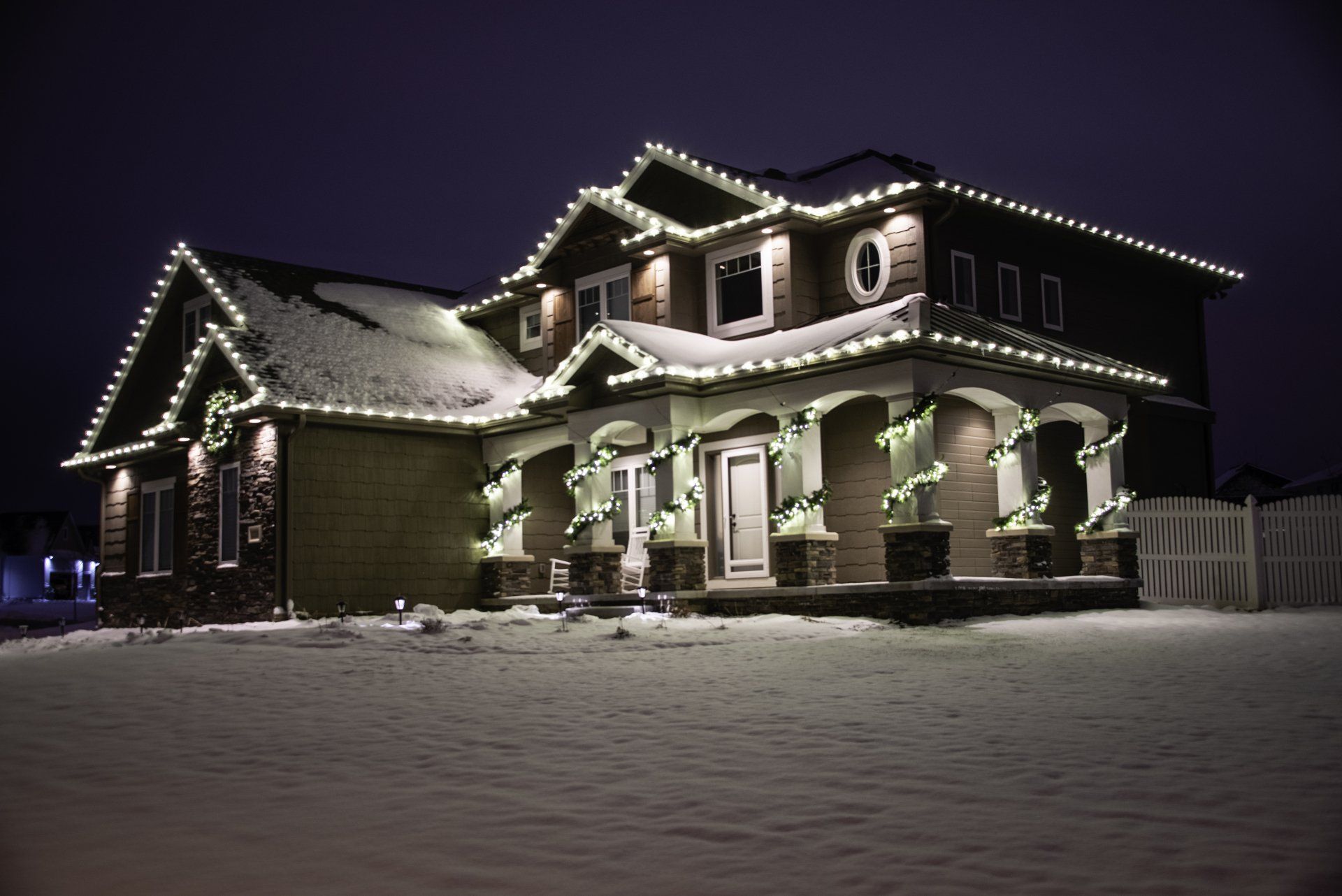 A large house is decorated with christmas lights at night.